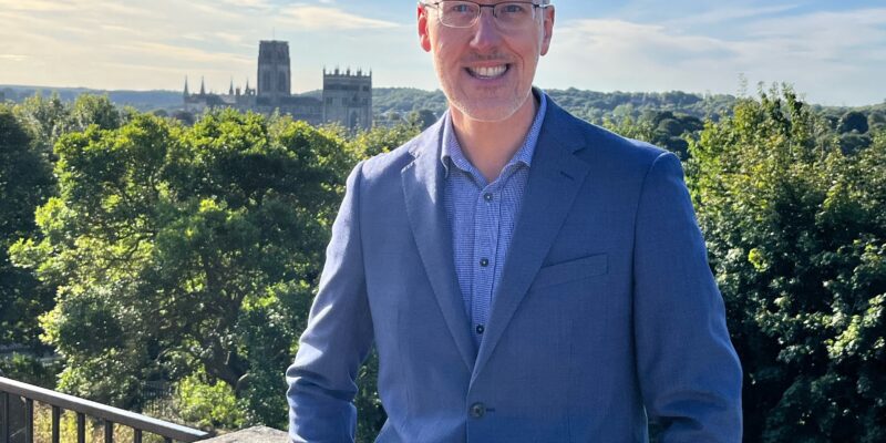 Photograph of Martyn Stenton in front of a view of Durham Cathedral