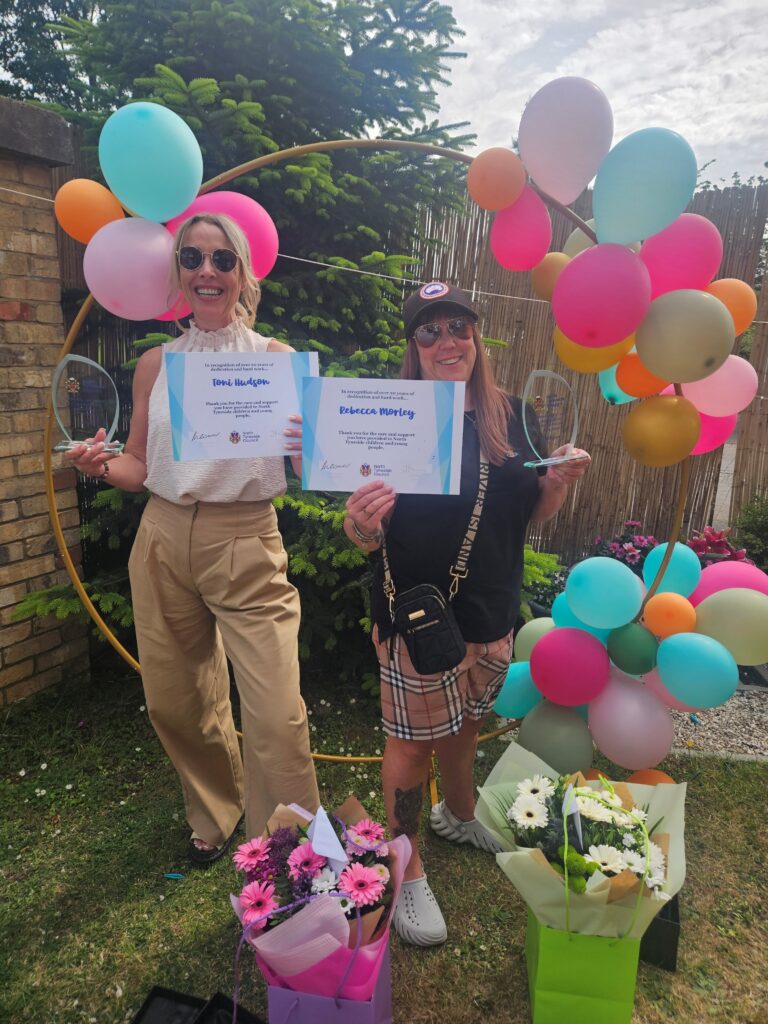 Photograph of two people holding certificates, smiling