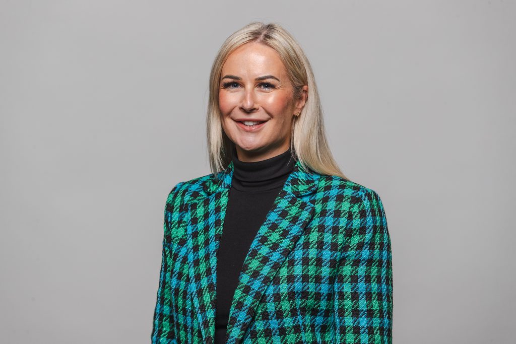 An image of Alison Sutherland, Executive Director of Children's Services as Hartlepool Borough Council. Alison has blonde hair and is wearing a blue and green checked blazer while smiling for a head on photo.